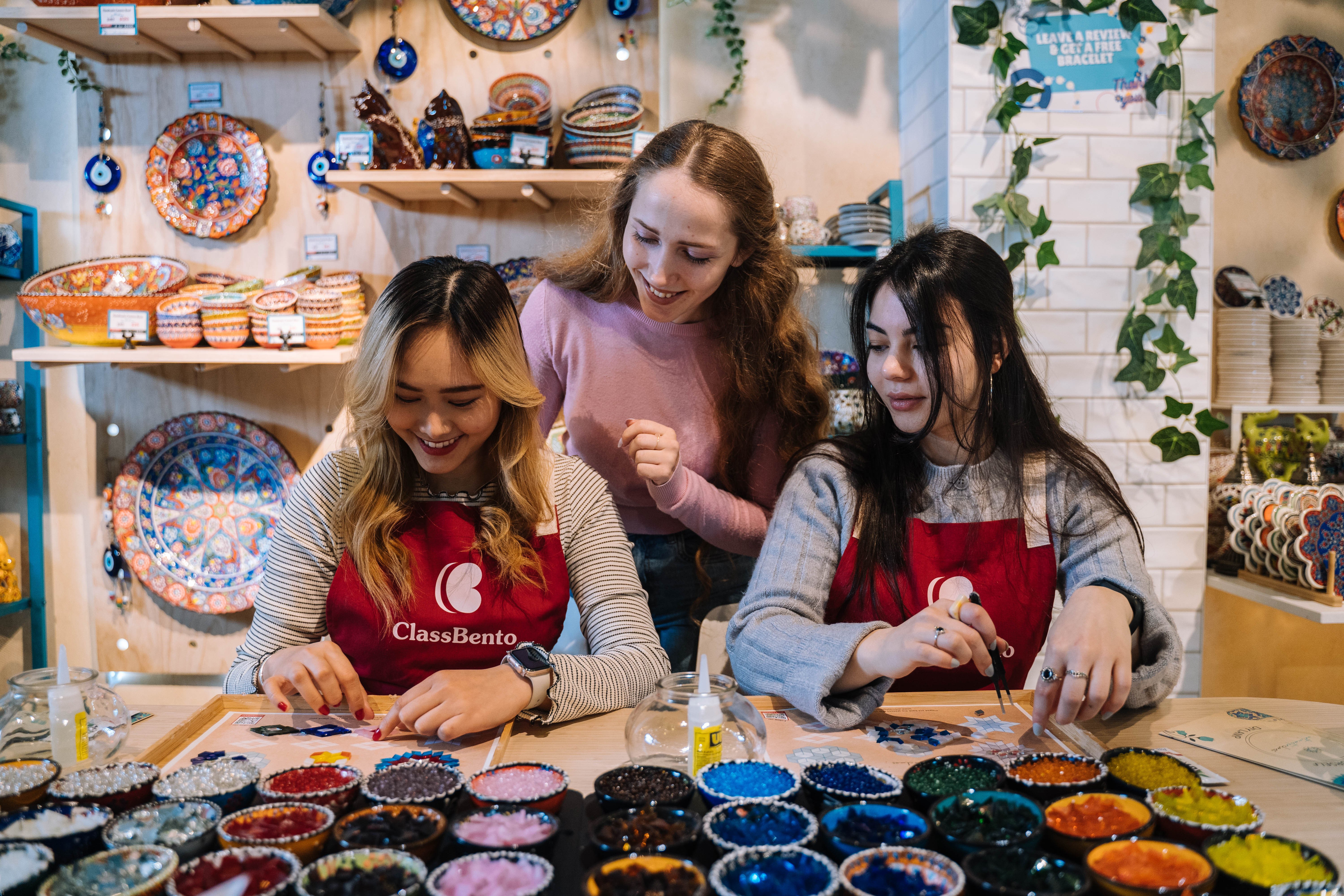 Teacher helping two students at a mosaic-making class